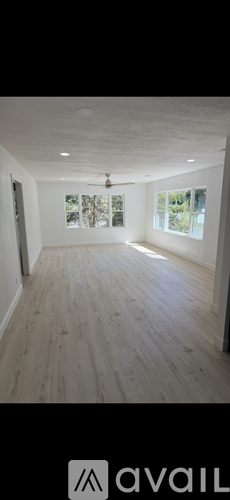 A spacious room with wooden flooring and a ceiling fan.