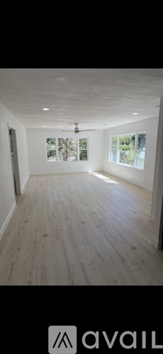 A spacious room with wooden flooring and a ceiling fan.