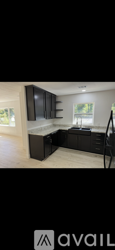 A modern kitchen with black cabinets and a wooden floor.