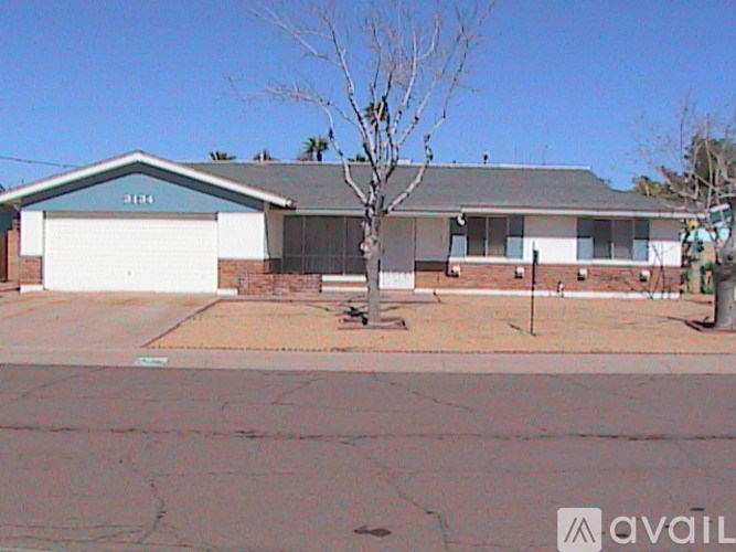 A house with a garage and a tree in front.