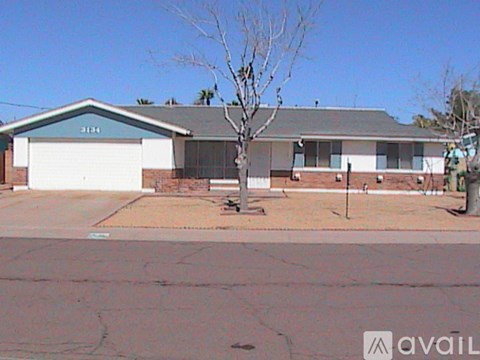 A house with a garage and a tree in front.