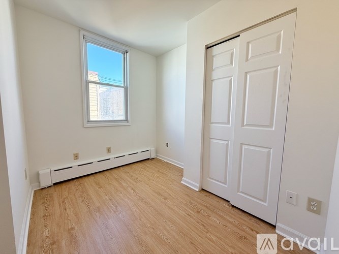 A room with a white door, window, and wooden floor.