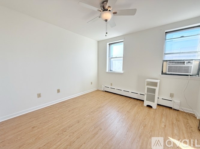 A room with a ceiling fan and wooden flooring.