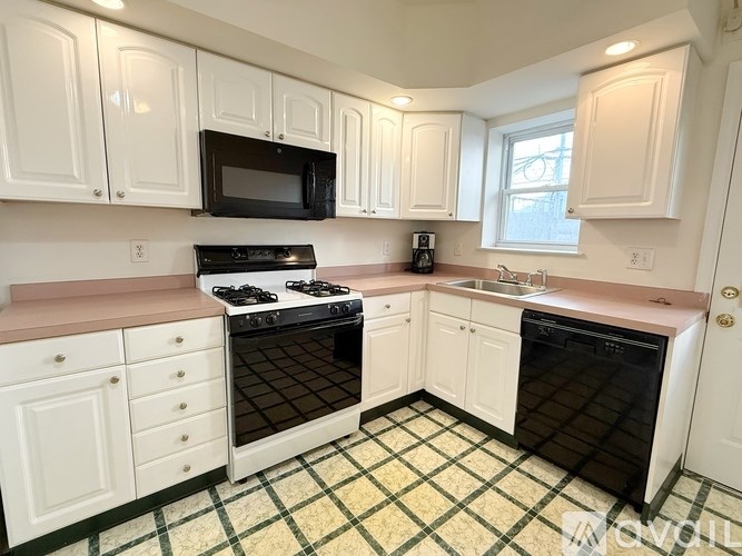A kitchen with white cabinets and black appliances.