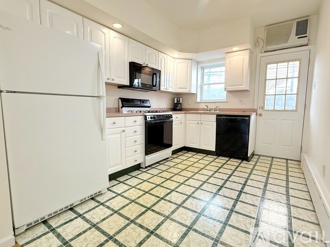 A kitchen with white appliances and black counter tops.