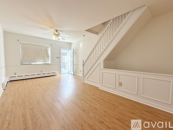 A spacious room with wooden floors and a staircase leading to another level.