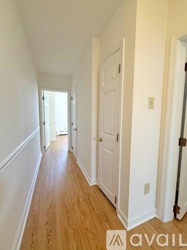 A hallway with a white door and Avail logo.
