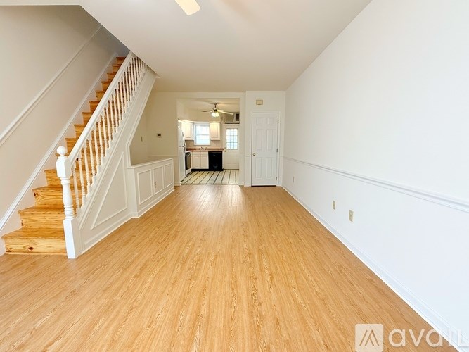 A spacious room with wooden floors and a staircase leading to the upper level.