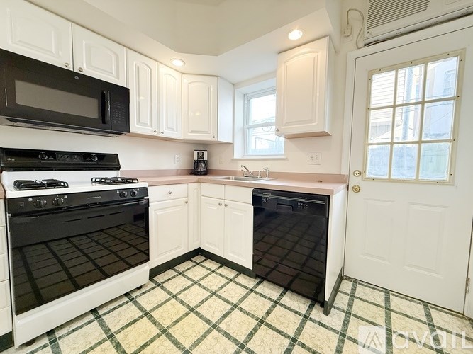 A kitchen with black and white appliances and a checkered floor.