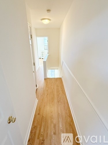 A hallway with wooden floors and white walls.