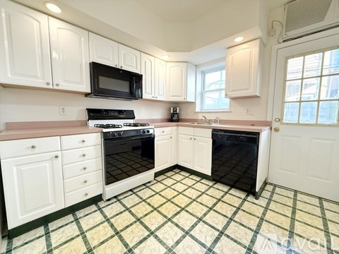 A kitchen with white cabinets and a black microwave.