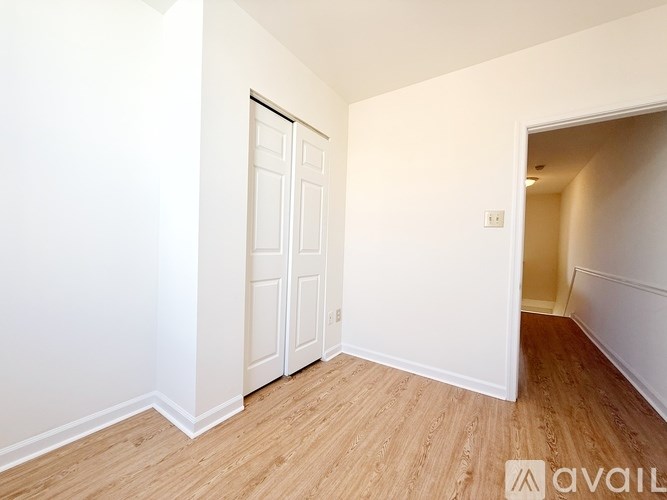A room with a white door and wooden flooring.