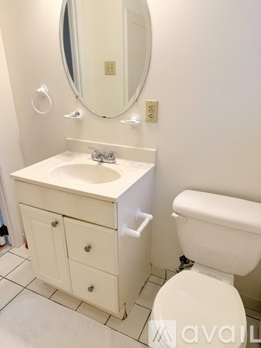 A white bathroom with a toilet, sink and mirror.