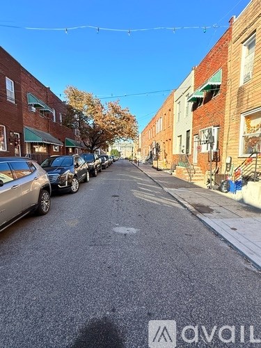 A street lined with parked cars and buildings on either side.