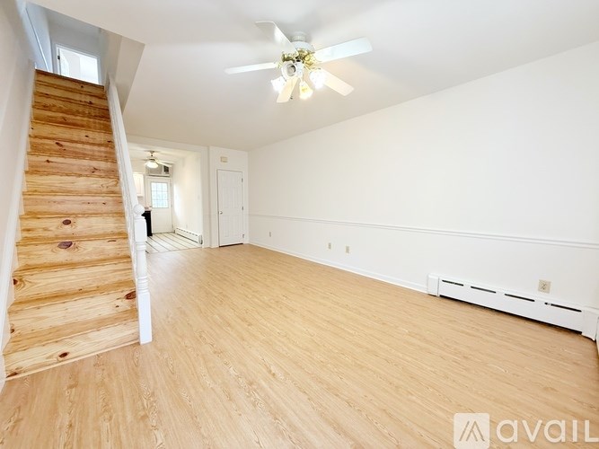 A spacious room with wooden floors and a staircase leading to another level.