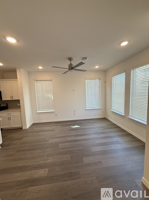 A spacious kitchen with a fan and wooden flooring.