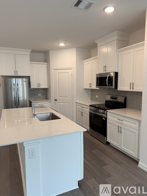 A kitchen with white cabinets and a door open to a pantry.