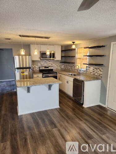 A kitchen with a white island and wooden floors.
