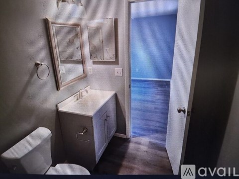 A bathroom with a toilet, sink, and mirror.
