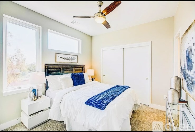 A bedroom with a bed, a ceiling fan, and a window.