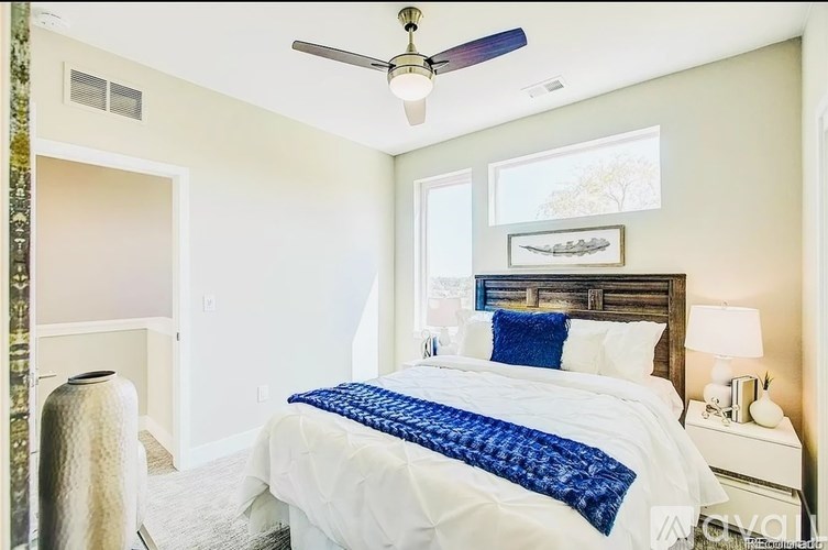 A bedroom with a bed, a ceiling fan, and a nightstand.