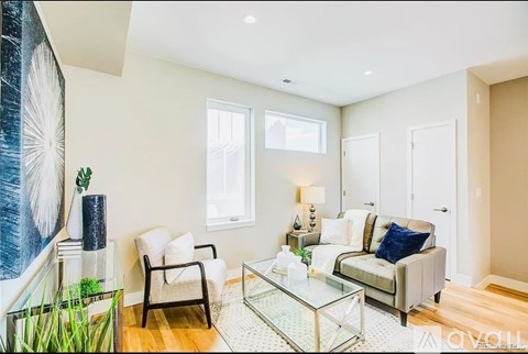 A living room with a glass coffee table and a large painting on the wall.