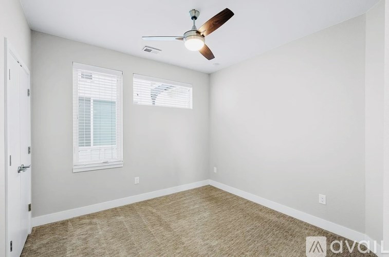 A room with a ceiling fan and two windows.