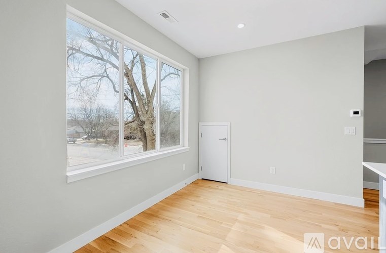 A room with a large window and a wooden floor.