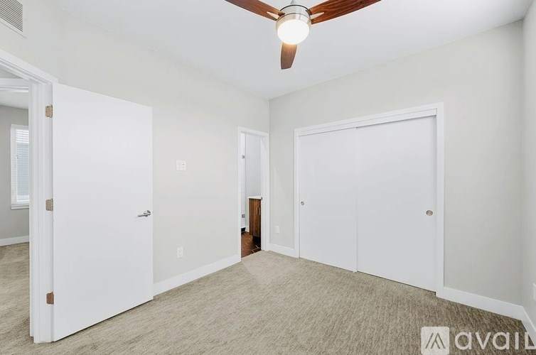 A room with a ceiling fan and three doors.