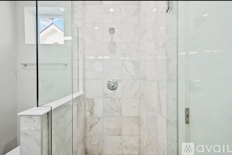 A bathroom with a glass shower stall and marble tiles.
