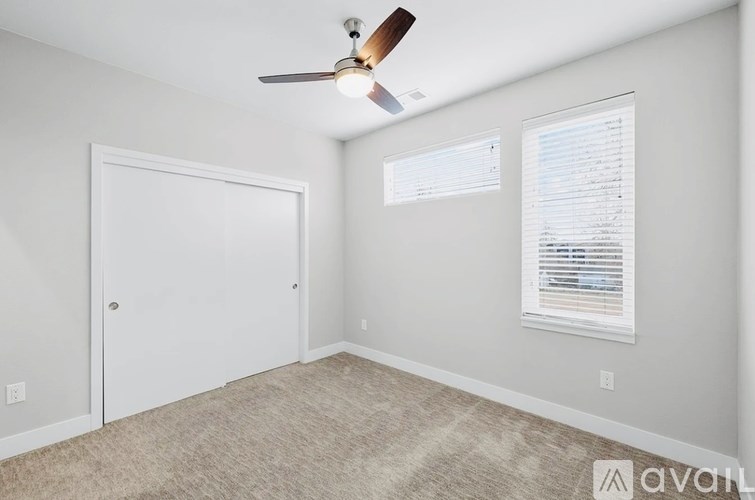 A room with a ceiling fan and a window with blinds.