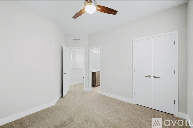 A room with a ceiling fan and three doors.