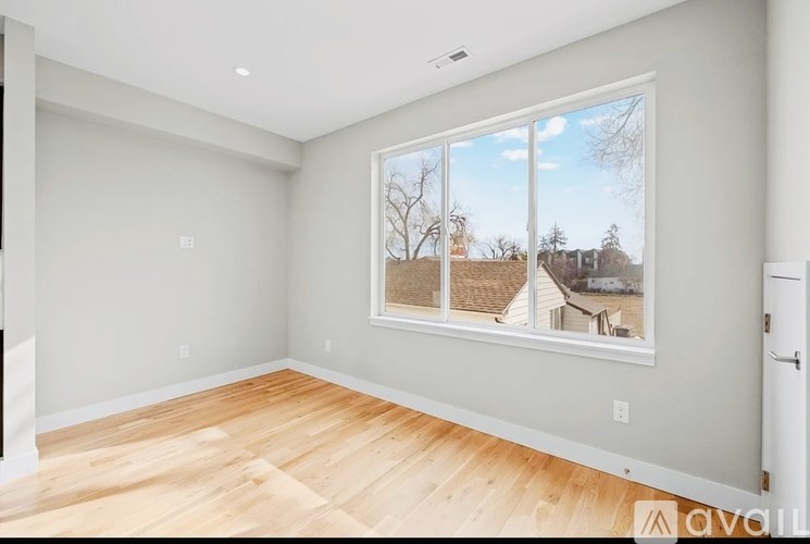 A room with a large window showing a view of a house and trees.