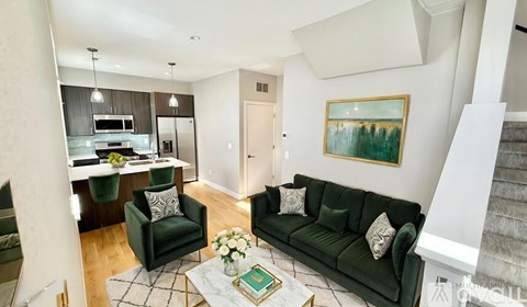 A living room with a green couch and a painting on the wall.