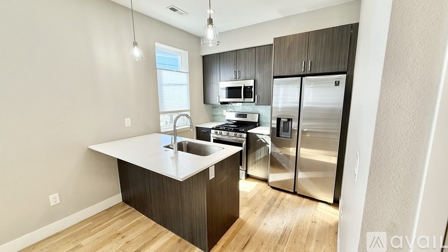 A modern kitchen with stainless steel appliances and wooden flooring.