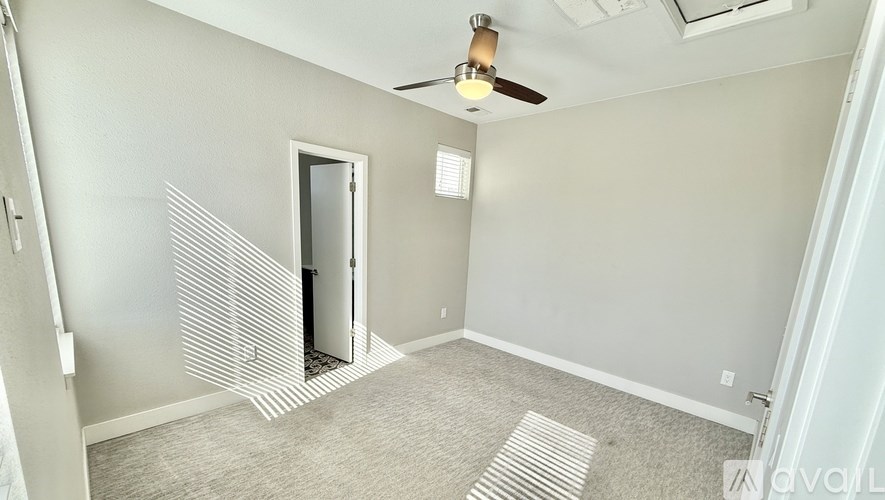A room with a ceiling fan and a door leading to a hallway.