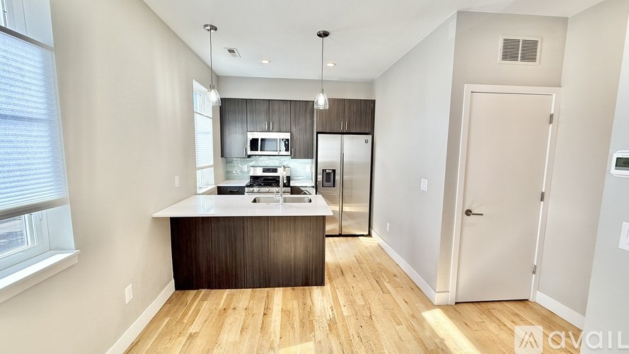 A modern kitchen with wooden floors and a white countertop.