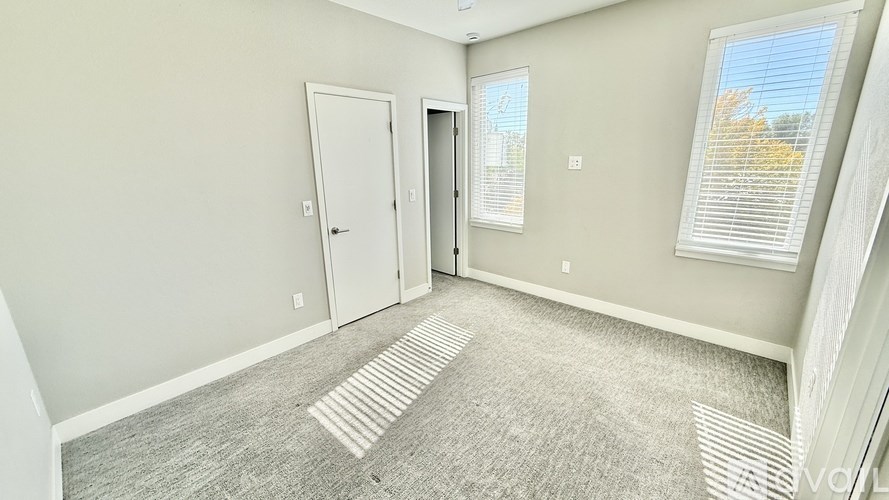 A room with a carpeted floor and two doors.