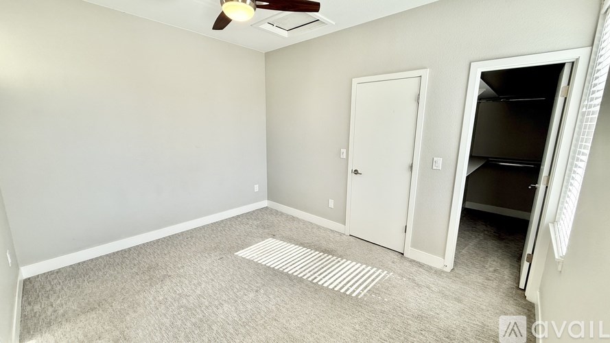 A room with a carpeted floor and a ceiling fan.