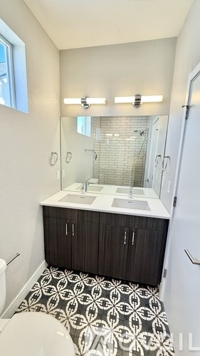 A bathroom with a toilet, sink, and mirror.