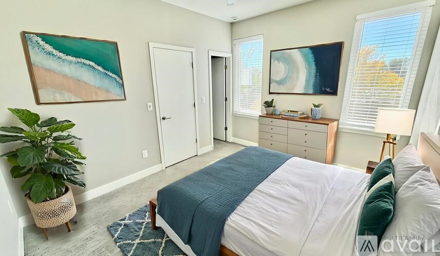 A bedroom with a bed, a desk, and a plant.