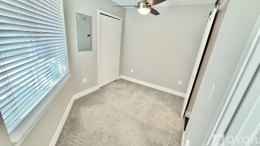 A room with a ceiling fan and a window with blinds.