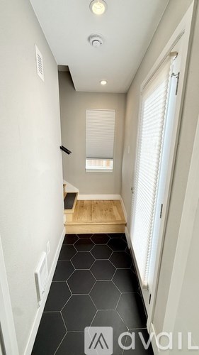 A hallway with a wooden floor and white walls.