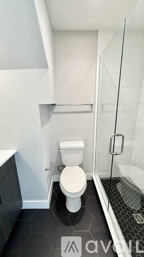 A white toilet in a small bathroom with a glass shower door.