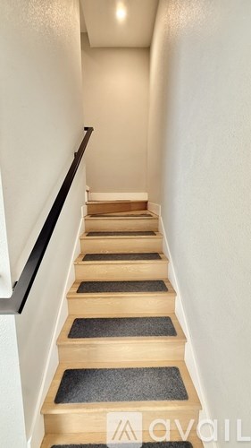 A staircase with wooden steps and a black handrail.