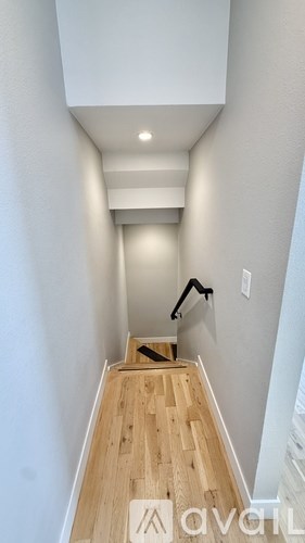 A hallway with wooden floors and white walls.
