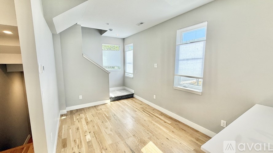 A spacious room with wooden flooring and a staircase leading to another level.