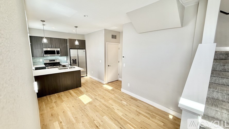 A modern kitchen with wooden floors and white walls.