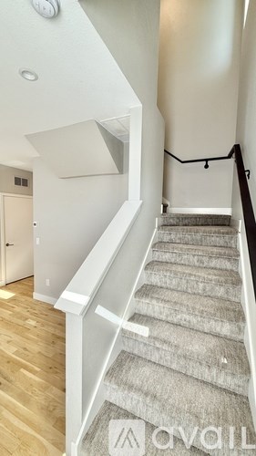 A staircase with a carpeted runner and a black handrail.