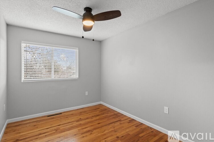 A room with a ceiling fan and a window with blinds.